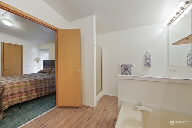 ensuite bathroom with ensuite bath, wood finished floors, vaulted ceiling, vanity, and a shower stall