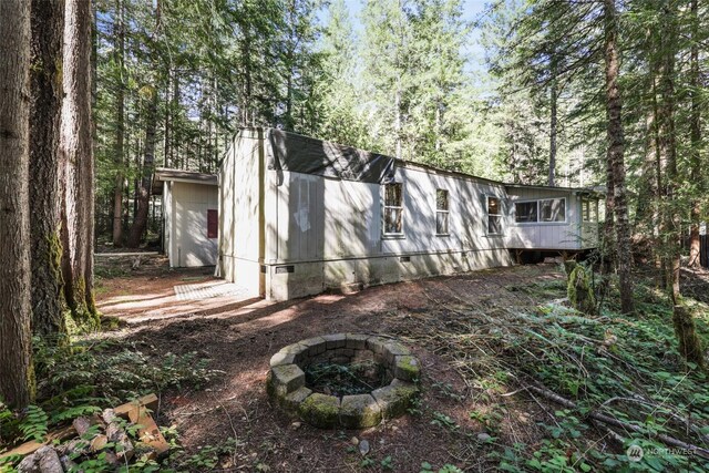 view of side of home featuring an outdoor fire pit and crawl space