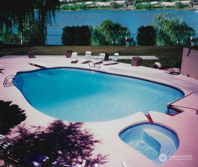 view of swimming pool featuring a water view, a patio area, and an in ground hot tub