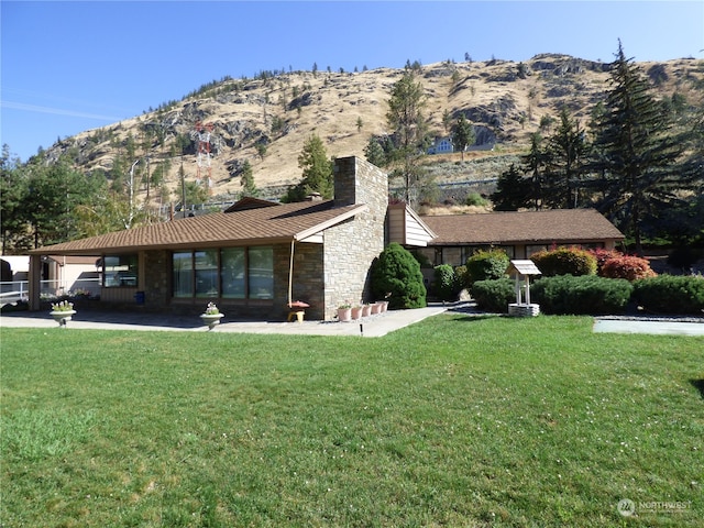 ranch-style home featuring a mountain view, a front lawn, and a carport