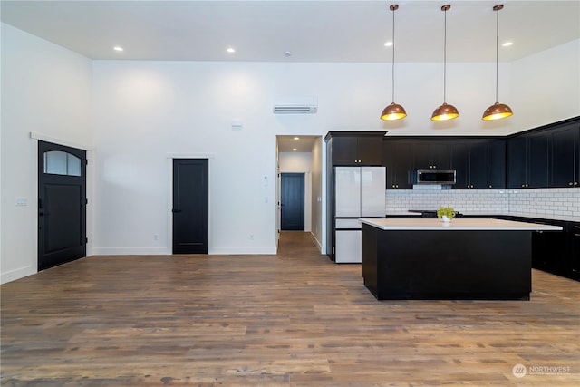 kitchen featuring pendant lighting, white refrigerator, light hardwood / wood-style flooring, and a kitchen island