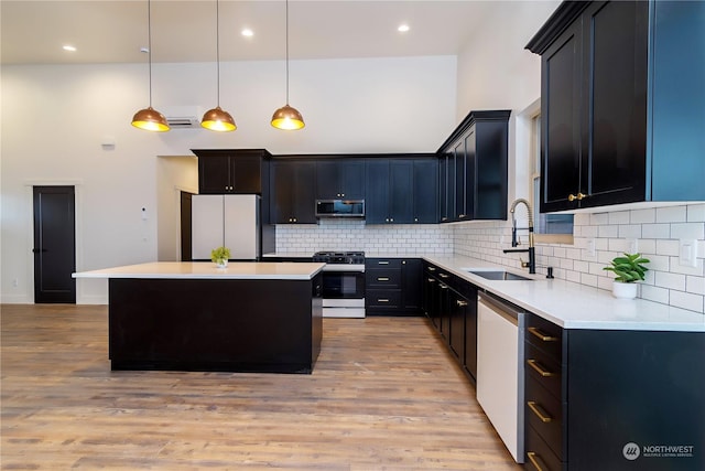 kitchen with pendant lighting, a center island, sink, light hardwood / wood-style flooring, and stainless steel appliances