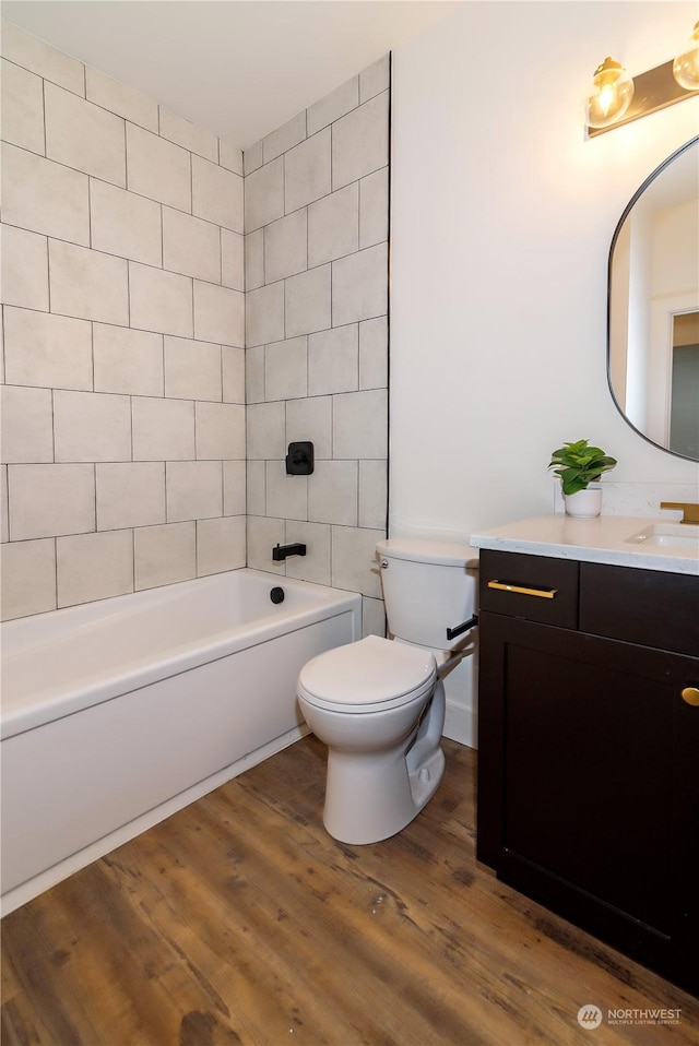 full bathroom featuring vanity, hardwood / wood-style flooring, toilet, and tiled shower / bath combo