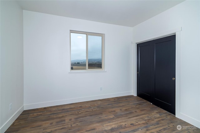 unfurnished bedroom with dark hardwood / wood-style flooring and a closet