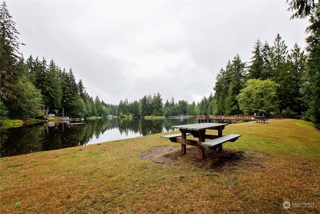 view of home's community featuring a lawn, a water view, and a wooded view