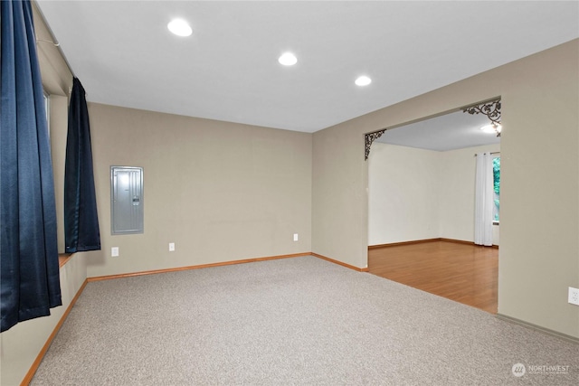 carpeted empty room featuring recessed lighting, electric panel, baseboards, and wood finished floors