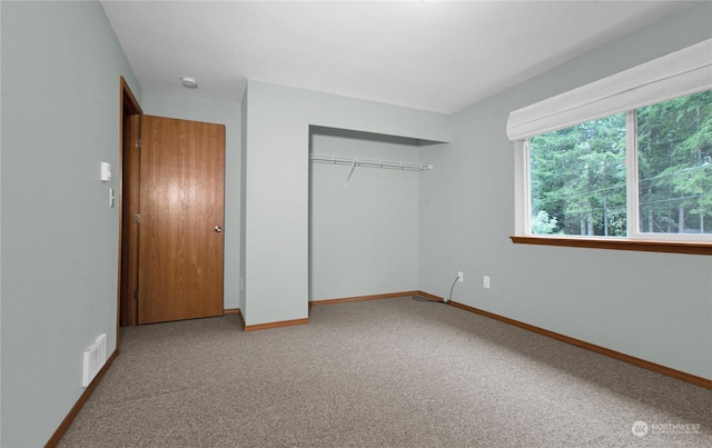 unfurnished bedroom featuring carpet floors, baseboards, visible vents, and a closet