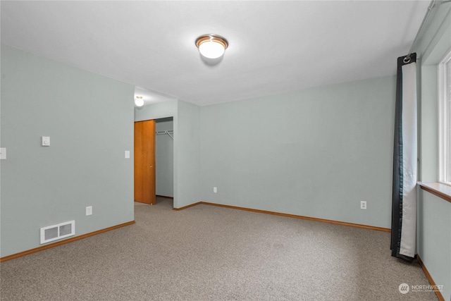 unfurnished room with carpet, visible vents, and baseboards