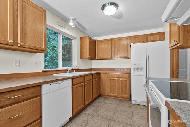 kitchen featuring white appliances, brown cabinets, a sink, and light countertops