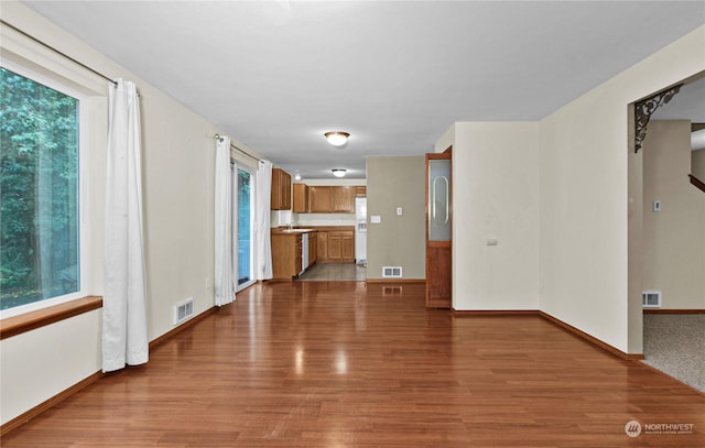 unfurnished living room with a wealth of natural light, wood finished floors, and visible vents