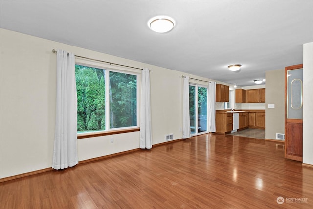 unfurnished living room featuring baseboards, a sink, visible vents, and light wood-style floors