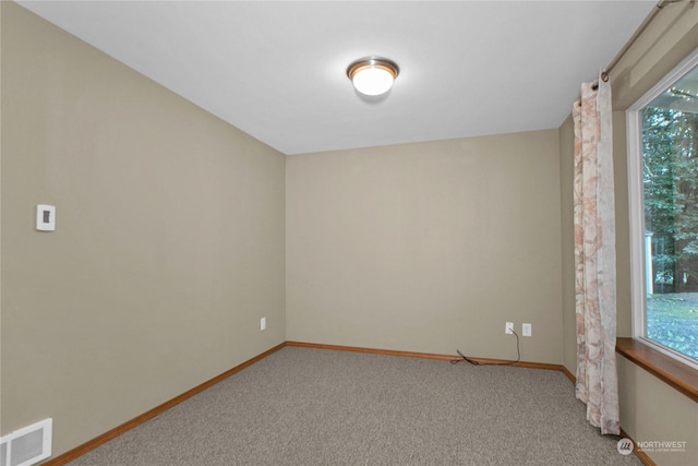 empty room with baseboards, visible vents, and carpet flooring