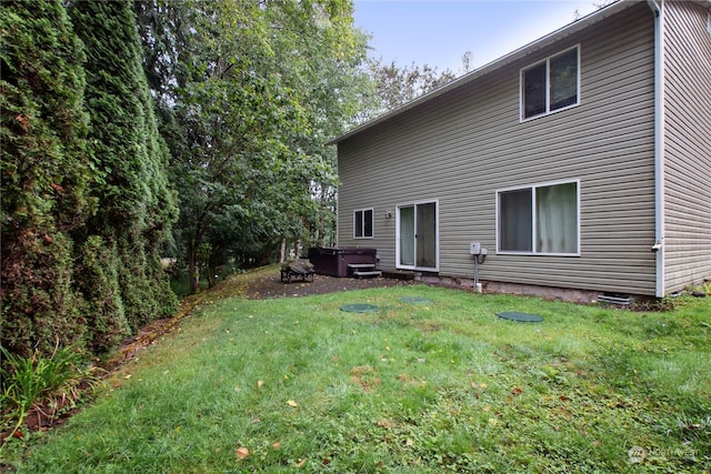 back of house with a lawn and a hot tub