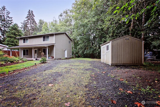 exterior space with a storage shed, driveway, covered porch, and an outdoor structure