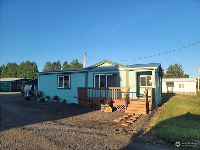 manufactured / mobile home featuring a front lawn and a carport