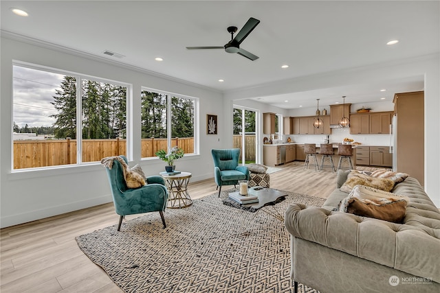 living room with ceiling fan, light hardwood / wood-style floors, and crown molding