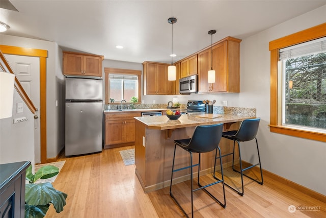 kitchen with light wood-type flooring, stainless steel appliances, sink, and a breakfast bar