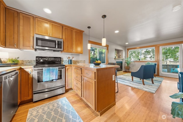 kitchen featuring pendant lighting, a healthy amount of sunlight, kitchen peninsula, and stainless steel appliances