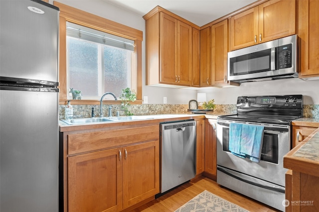 kitchen featuring stainless steel appliances, sink, and light wood-type flooring