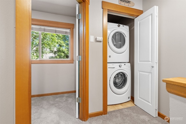 clothes washing area with light colored carpet and stacked washer and dryer