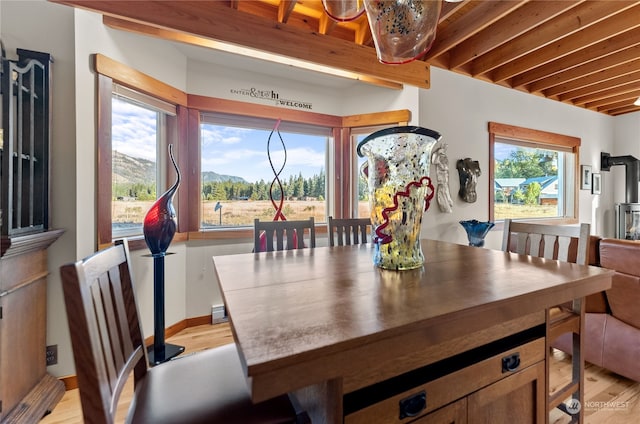 dining area featuring beamed ceiling, a mountain view, and light hardwood / wood-style floors