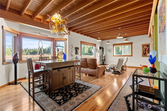 dining area with a notable chandelier, beam ceiling, light wood-type flooring, and wooden ceiling