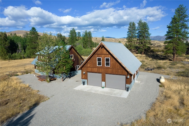 view of front of house featuring a detached garage, a mountain view, metal roof, and an outbuilding