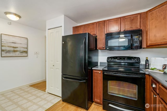 kitchen featuring black appliances, baseboards, brown cabinetry, and light floors