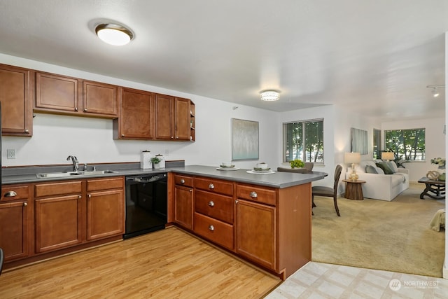 kitchen with black dishwasher, dark countertops, open floor plan, a sink, and a peninsula