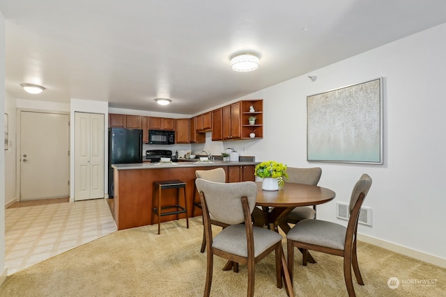 dining room featuring light floors, baseboards, visible vents, and light colored carpet