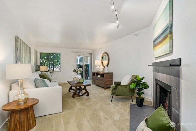 carpeted living area featuring rail lighting, a lit fireplace, and baseboards