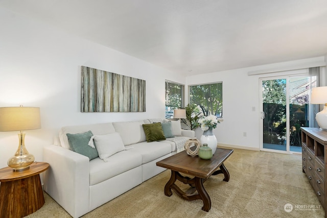 living room featuring light carpet, plenty of natural light, and baseboards