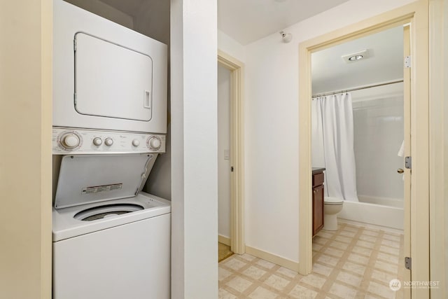 clothes washing area with light floors, baseboards, laundry area, and stacked washer / dryer