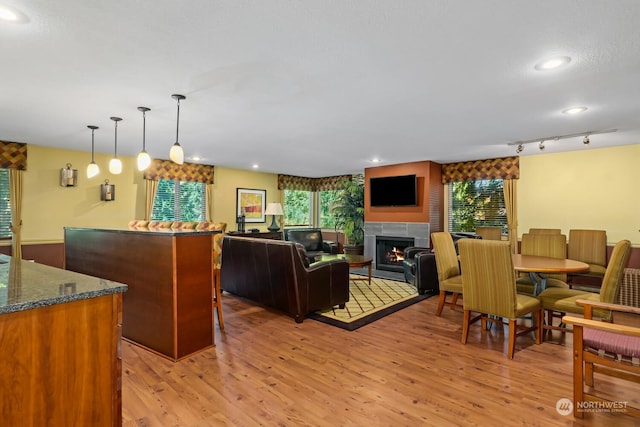 interior space featuring recessed lighting, a warm lit fireplace, rail lighting, and light wood finished floors