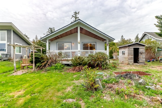 back of property featuring a storage unit, a porch, a lawn, and an outdoor structure