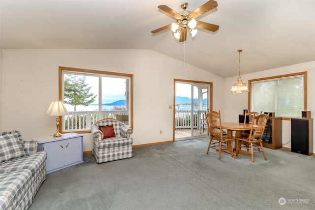 dining space with ceiling fan with notable chandelier, a mountain view, lofted ceiling, and carpet flooring