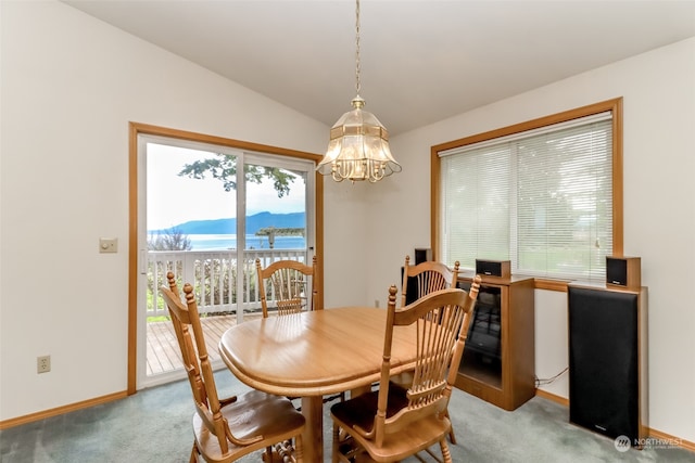 dining room with carpet floors, vaulted ceiling, an inviting chandelier, and a mountain view