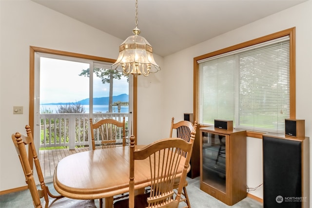 carpeted dining area featuring lofted ceiling, a mountain view, a chandelier, and a healthy amount of sunlight