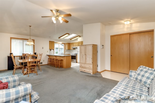 living room with lofted ceiling with skylight, light carpet, ceiling fan, and plenty of natural light