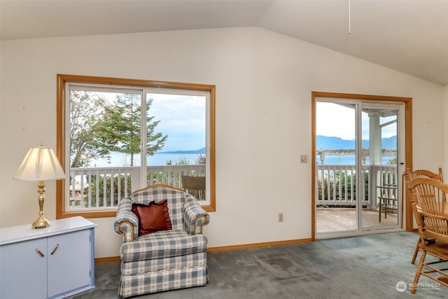 sitting room featuring dark carpet, lofted ceiling, a mountain view, and a healthy amount of sunlight