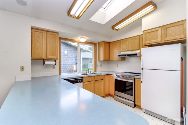 kitchen featuring vaulted ceiling with skylight, sink, kitchen peninsula, white appliances, and light brown cabinetry