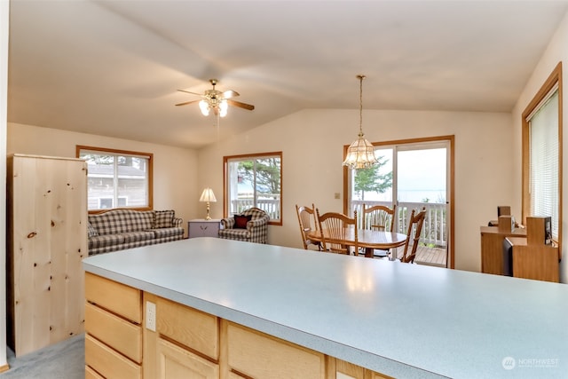 kitchen featuring light brown cabinets, lofted ceiling, hanging light fixtures, and a healthy amount of sunlight