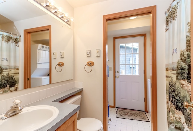 bathroom with stacked washer / dryer, vanity, and toilet