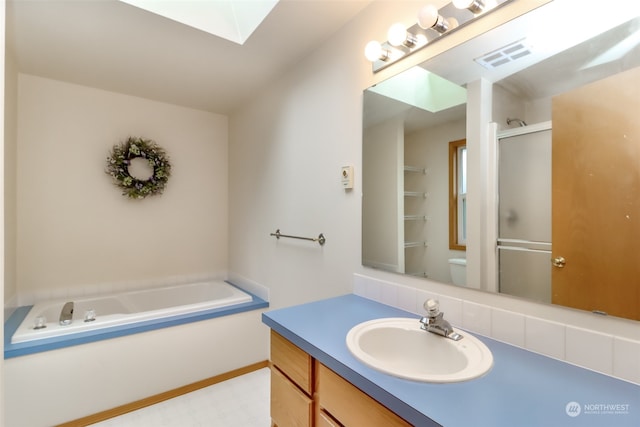 full bathroom featuring separate shower and tub, vanity, toilet, and a skylight