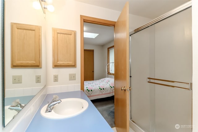 bathroom with a skylight, a shower with door, and sink