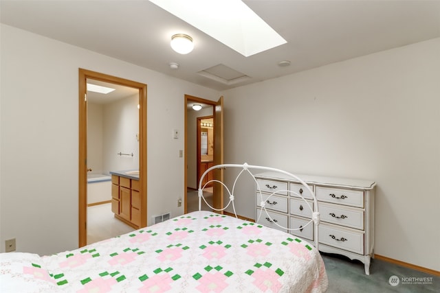 carpeted bedroom with connected bathroom and a skylight