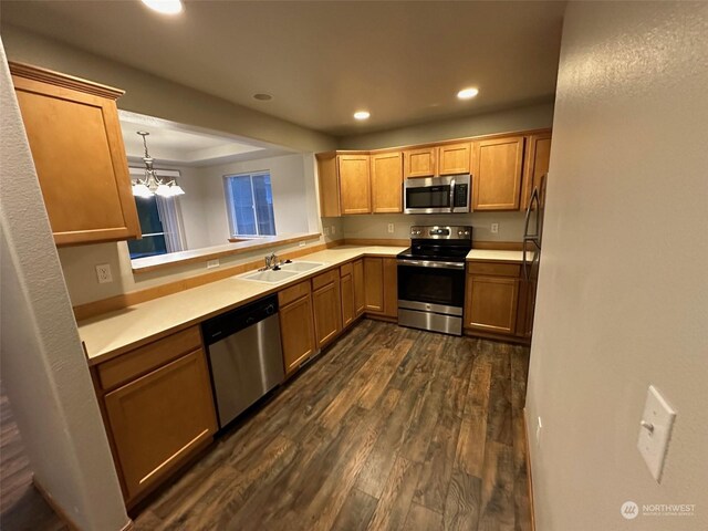 kitchen featuring an inviting chandelier, appliances with stainless steel finishes, sink, dark wood-type flooring, and pendant lighting