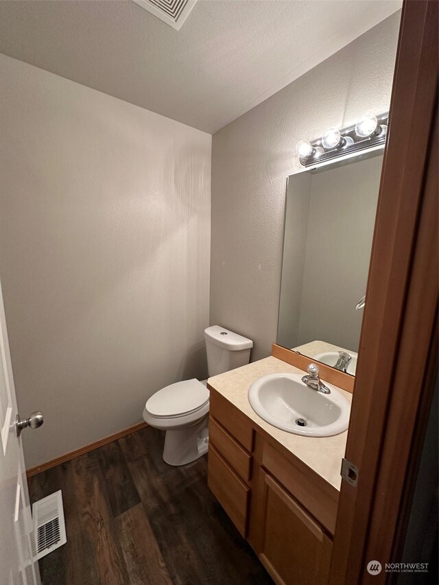 bathroom with vanity, toilet, hardwood / wood-style flooring, and a textured ceiling