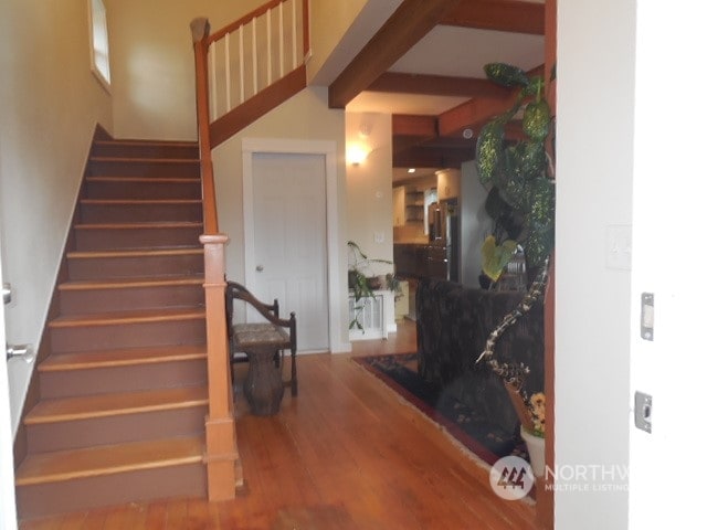 stairway with beamed ceiling and hardwood / wood-style floors