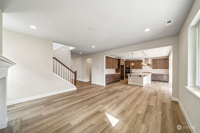 unfurnished living room with sink and light hardwood / wood-style flooring